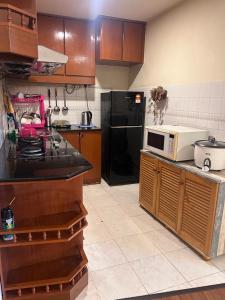 a kitchen with a white microwave and a black refrigerator at Riverbank suites unit 405 in Kuching