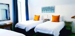金尤西The Osprey Hotel的两张带橙色枕头的床