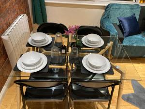 Central Sheffield 3BED 3BATH V Pent-Apartment في شيفيلد: طاولة طعام مع أطباق وكراسي بيضاء