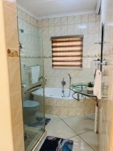 a bathroom with a shower and a toilet and a tub at Olebone_C-rane Lodge in Phalaborwa