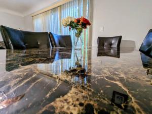 une table en verre avec un vase et des fleurs sur lui dans l'établissement Beautiful Home in Dearborn Heights, Comfy Beds, à Dearborn Heights