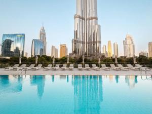 einen Pool mit Stühlen und eine Stadt im Hintergrund in der Unterkunft Prime Retreats @ Address Residence Opera By Emaar in Dubai