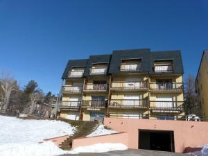 un immeuble avec un toit noir dans la neige dans l'établissement Les Sorbiers - Grand T4 ensoleillé avec Vue Panoramique, à Font-Romeu-Odeillo-Via