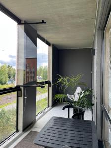 balcón con mesa, sillas y ventanas grandes en Tikka Apartments, en Jyväskylä