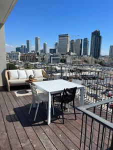 Superbe Penthouse Terrasse avec vue Mer في تل أبيب: طاولة وكراسي على شرفة مطلة على مدينة
