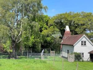 an old white house in a field with a tree at Beautiful 2 bed Oast - 15 acre farm - Tunbridge Wells in Royal Tunbridge Wells