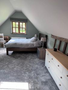 a bedroom with a bed and a dresser and a window at Beautiful 2 bed Oast - 15 acre farm - Tunbridge Wells in Royal Tunbridge Wells