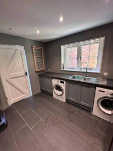 a kitchen with a sink and a washer and dryer at Beautiful 2 bed Oast - 15 acre farm - Tunbridge Wells in Royal Tunbridge Wells