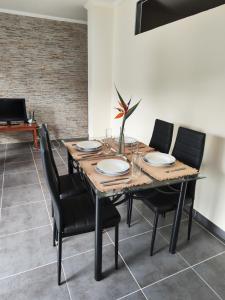 uma sala de jantar com uma mesa de madeira e cadeiras pretas em Quinta' Home em Ribeira da Janela