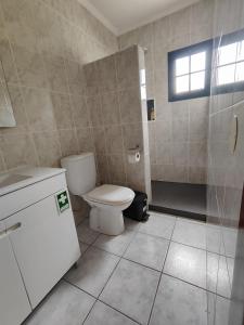 uma casa de banho com um WC branco e um chuveiro em Quinta' Home em Ribeira da Janela
