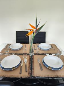 a table with plates and a flower in a vase at Quinta' Home in Ribeira da Janela