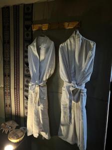 two white robes are hanging on a rack at Starwatching Private Camp in Ḩawīyah