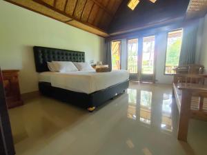 a bedroom with a large bed in a room with windows at Pondok Siola in Labuhanpandan