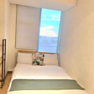 Cama en habitación con ventana grande en Resort Living 2BR Azure Urban Residences w/ Wi-Fi en Parañaque