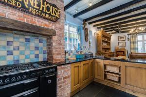 una cucina con piano cottura e muro di mattoni di Historic Osborne House very close to the beach a Looe Altre 60 foto