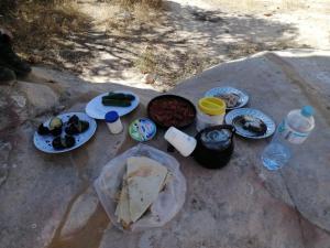 ein Tisch mit Tellern mit Essen und Flaschen Wasser in der Unterkunft - Trekking from Dana to Petra in Dana
