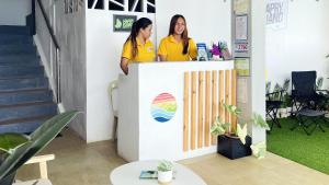 Due donne in piedi al bancone di un ufficio di Happy Island Inn a Virac