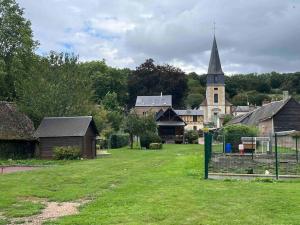 un village avec une église et une cour avec une clôture dans l'établissement « Au Fil du Bec », au Bec-Hellouin