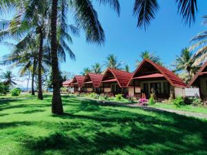 una fila di cottage sulla spiaggia con palme di Pondok Siola a Labuhanpandan