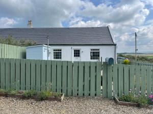 una cerca verde frente a una casa blanca en No 2 Ramageton, en Troon