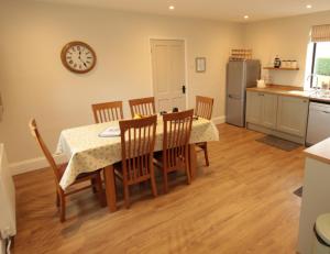 a kitchen with a table and chairs and a clock on the wall at Moo Cow Cottage Self Catering in Oakham