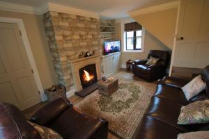 sala de estar con sofá y chimenea en Moo Cow Cottage Self Catering, en Oakham