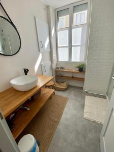 La salle de bains est pourvue d'un lavabo blanc et d'un miroir. dans l'établissement LES PETITS ROYS - Proche centre ville - Cosy, à Châteauroux