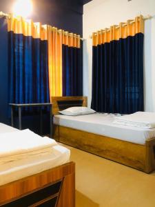 Duas camas num quarto com cortinas azuis e laranja em Royal residency em Tindummal
