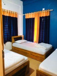two beds in a room with blue walls and curtains at Royal residency in Tindummal