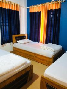 2 Betten in einem Zimmer mit blauen Wänden und Vorhängen in der Unterkunft Royal residency in Tindummal