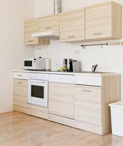 a kitchen with white appliances and wooden cabinets at MINIMALISTIC STUDIO NEAR NASCHMARKT in Vienna