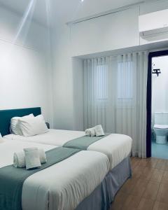 Duas camas num quarto branco com um WC em Local House Lisbon em Lisboa