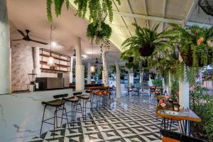 a restaurant with plants and a bar with stools at 花语岸·度假酒店(H·Flora Hotel) in Chiang Mai