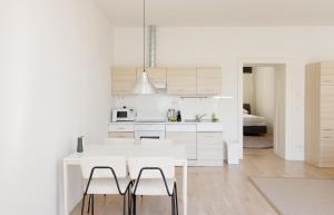 a white kitchen with a white table and chairs at MINIMALISTIC STUDIO NEAR NASCHMARKT in Vienna
