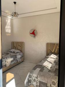 a bedroom with two beds and a mirror on the wall at Appartement Cosy-Alliance darna,Mehdia (kenitra) in Kenitra