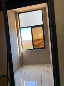 an empty room with a window and a tiled floor at Appartement Cosy-Alliance darna,Mehdia (kenitra) in Kenitra