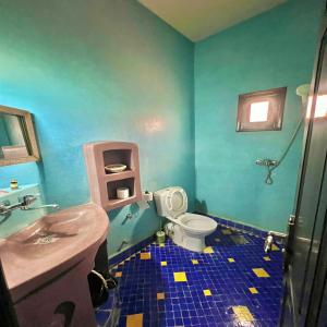 a blue bathroom with a toilet and a sink at Riad Hassi Labied Merzouga in Merzouga