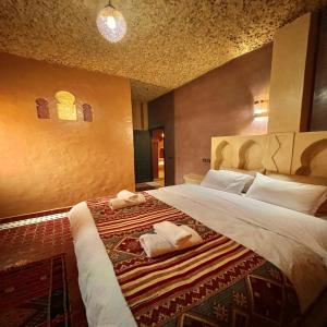 a bedroom with a large bed with towels on it at Riad Hassi Labied Merzouga in Merzouga