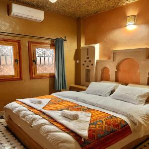 ein Schlafzimmer mit einem großen Bett mit Handtüchern darauf in der Unterkunft Riad Hassi Labied Merzouga in Merzouga