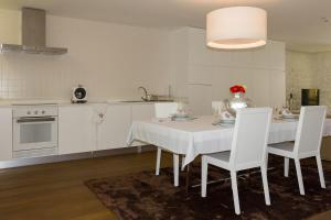 a kitchen with a white table and white chairs at Cantinho do Cantador in Riba de Mouro
