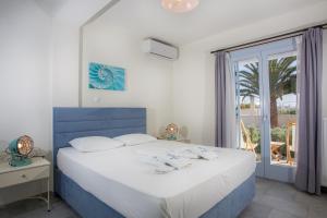 a bedroom with a blue and white bed and a window at Amphitrite Apartments Skyros in Skiros
