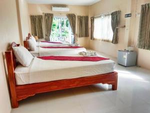 two twin beds in a room with a window at Khao-Sok Bed and Breakfast in Khao Sok National Park