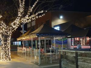 a restaurant with tables and chairs under umbrellas at night at Sunbury Central in Sunbury