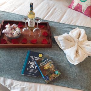 Bett mit einem Tablett mit Weingläsern und einem Buch in der Unterkunft The Cottage Angochagua in Ibarra