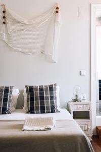 a white bedroom with a bed with black and white pillows at LEGASEA - Cascais Guesthouse in Cascais