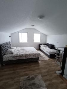 1 dormitorio con 2 camas, mesa y 2 ventanas en Vila Vasilisa, en Prijepolje