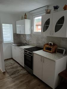 a kitchen with white cabinets and a sink and a stove at Vila Vasilisa in Prijepolje