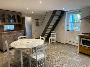 a kitchen with a table and chairs and a staircase at Montjoïa Le gîte bleu in Le Thor