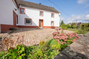 a large white house with a brick driveway at Ferienhaus Schneifel in Auw