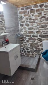 a bathroom with a stone wall with a shower at ΜΑΡΙΓΟΥΛΑΜ in Kalesménon